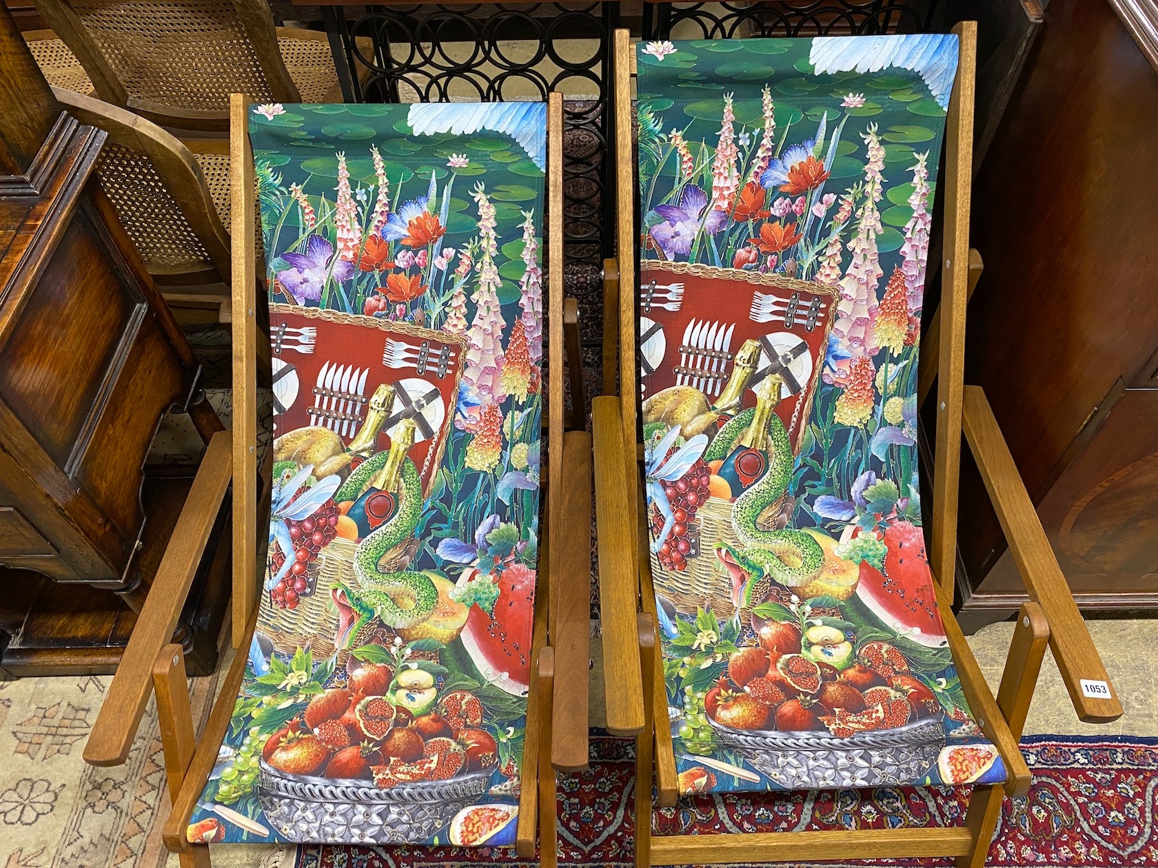 A pair of modern teak framed deck chairs with printed fabric panels